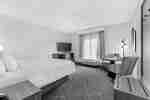 Habitación con cama King, sillas, mesa y televisor