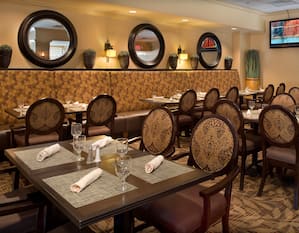 White Napkins and Drinking Glasses on Dining Tables, Chairs, Booth Seating, Wall Mirrors, and TV in Maxwell's Restaurant