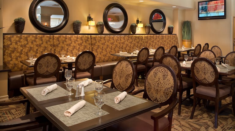 White Napkins and Drinking Glasses on Dining Tables, Chairs, Booth Seating, Wall Mirrors, and TV in Maxwell's Restaurant