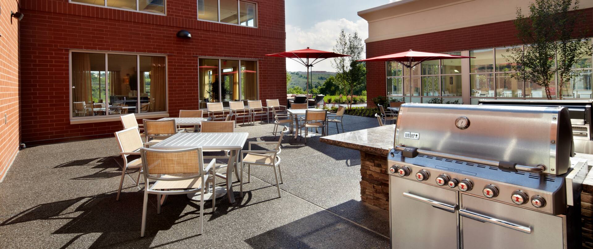 Outdoor Patio area with BBQ gril and dining tables with umbrellas