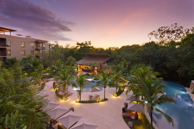 View at Sunset of Hotel Exterior and Pool Area with Palm Trees