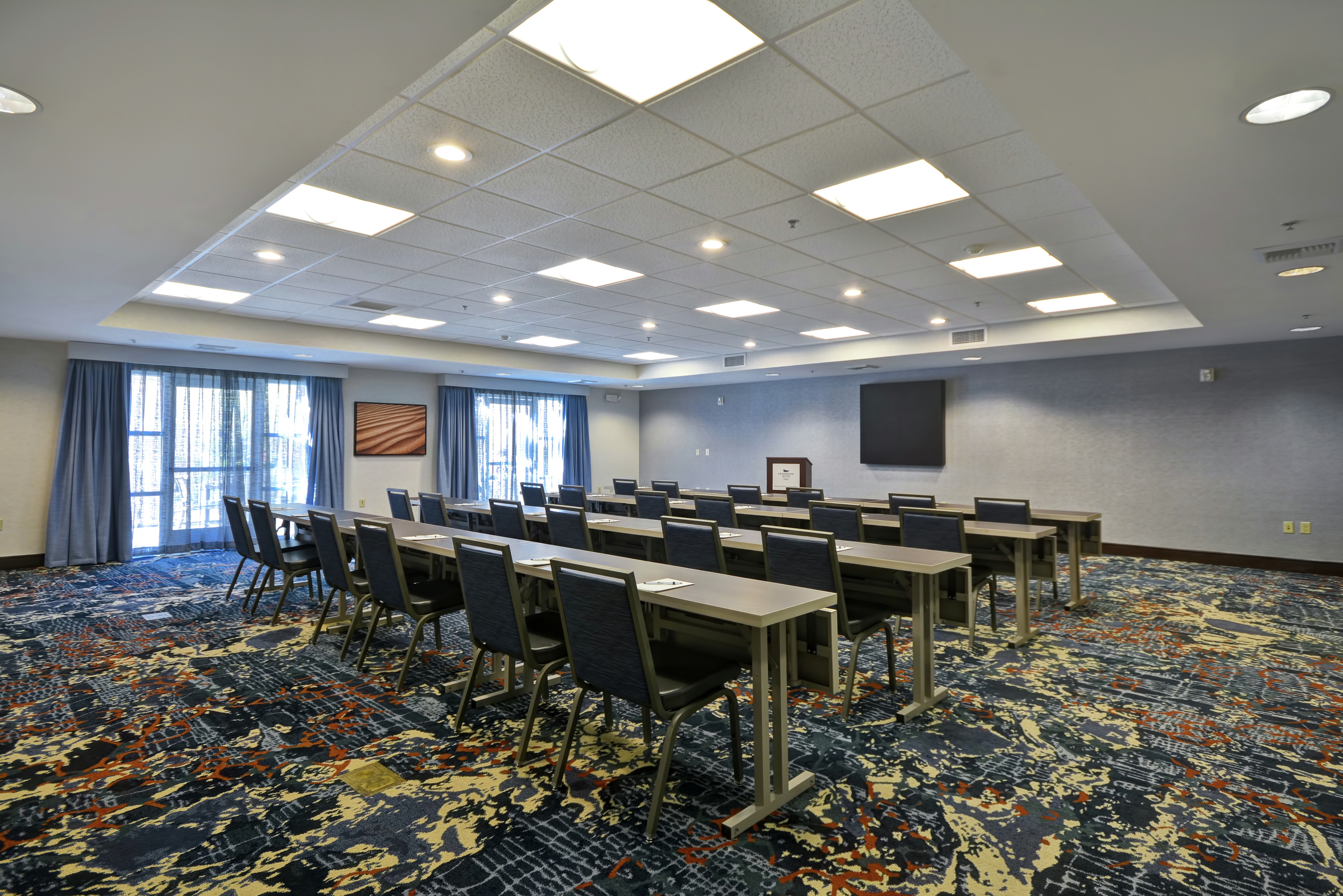 Classroom Setup in Meeting Room With Tables and Chairs Facing TV and Podium