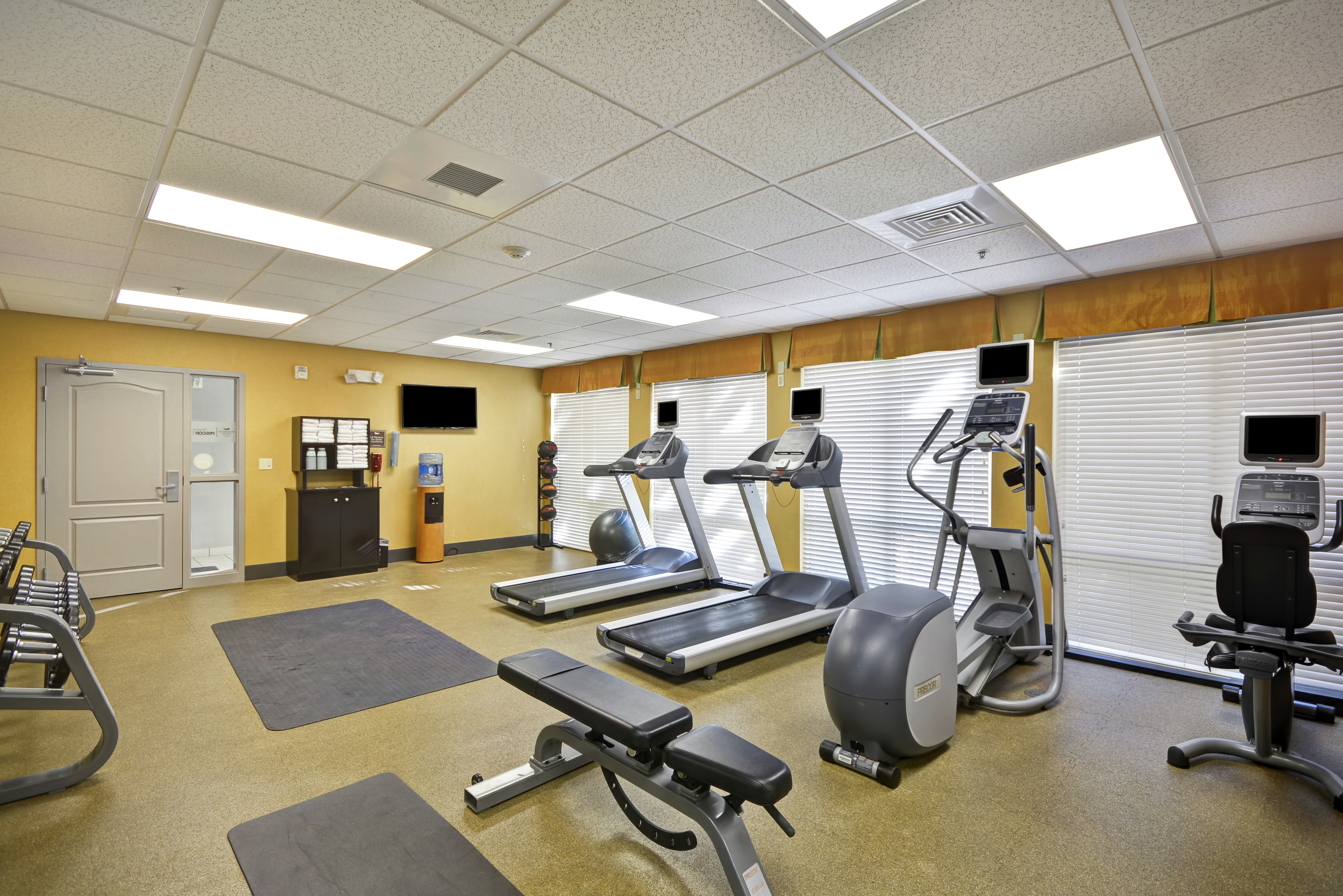 Fitness Center With Entry, Towel Station, Water Cooler, TV, Weight Balls, Stability Ball, Cardio Equipment, Weight Bench, and Free Weights
