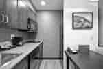 Suite Kitchen With Sink, Dishwasher, Coffee Maker, Microwave Over Stove With Twin Burners, Fridge, and Dining Table
