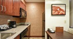 Suite Kitchen With Sink, Dishwasher, Coffee Maker, Microwave Over Stove With Twin Burners, Fridge, and Dining Table