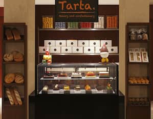 "Tarta Bakery and  Confectionary" Signage Above Display Case and Shelves With Baked Items For Sale