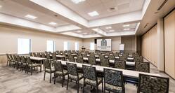 Ballroom in Classroom Setting with Long Tables and Chairs Facing Projector Screen with Outside Views