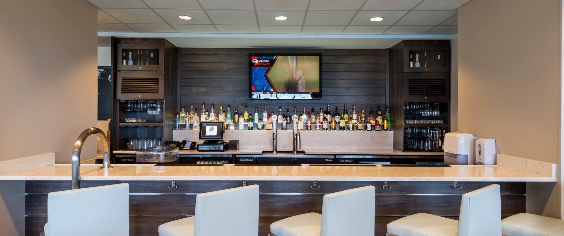 Front View of the Hotel Bar with TV and Five Bar Chairs