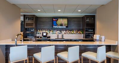 Front View of the Hotel Bar with TV and Five Bar Chairs