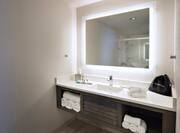 Sink/Vanity Under Mirror with Lights, Towels, and Toiletries in Suite Bathroom