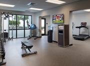 Free Weights, Weight Bench, TV Above Water Dispenser, and Two Treadmills in the Background