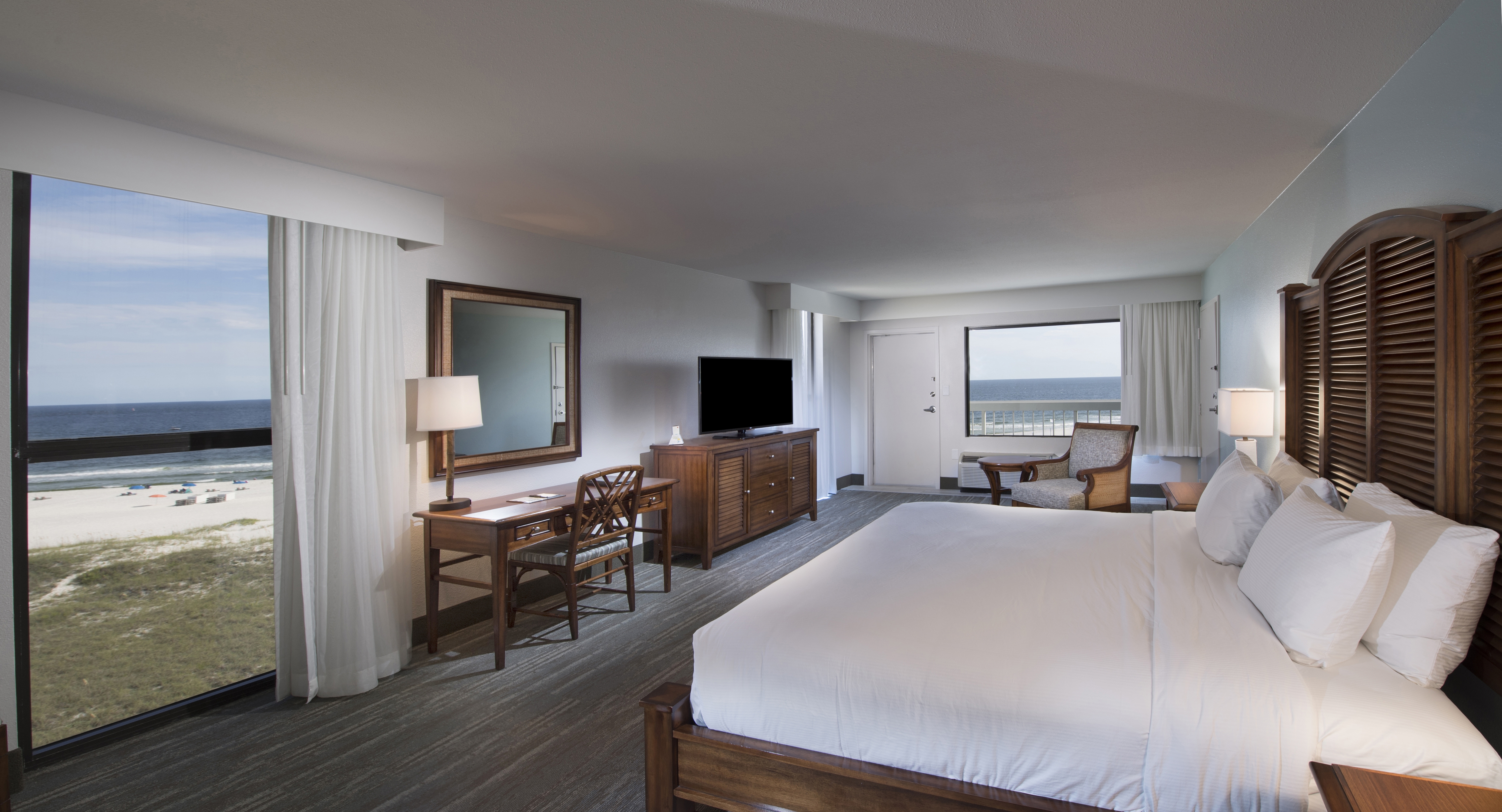 King Bed and Bedside Tables Facing Beach View, TV and Work Desk with Reading Chair in Corner by Window