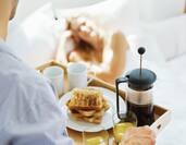 Man Carrying Tray of Room Service Food to Woman in Bed