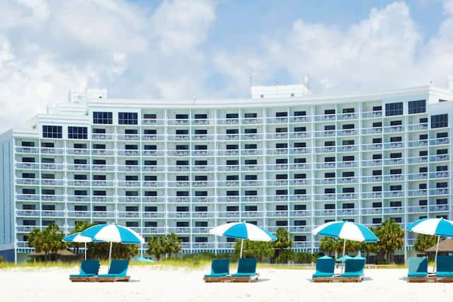 Daytime View of Loungers Under Sun Umbrellas by Hotel Exterior