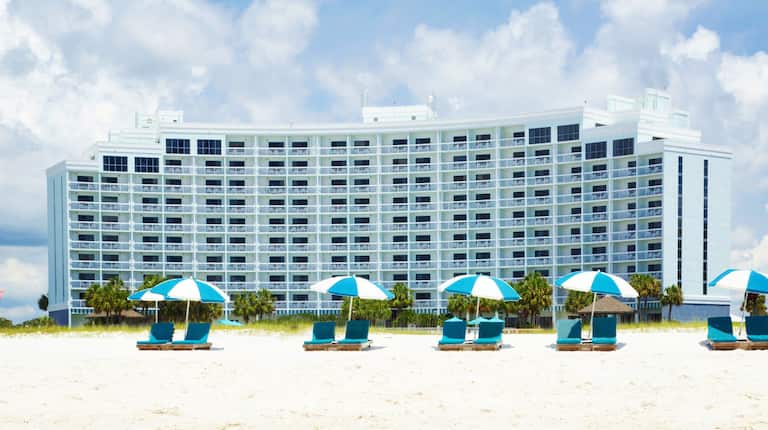 Daytime View of Loungers Under Sun Umbrellas by Hotel Exterior