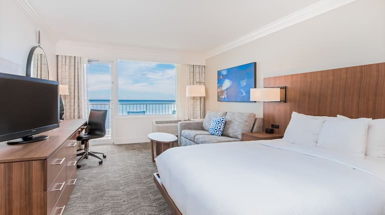 Chambre avec un très grand lit, canapé, table basse, bureau de travail et téléviseur HD