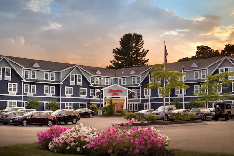 Hotel Exterior, Signage, Circle Drive, Flag Pole and Guest Cars on Parking Lot at Sunset