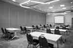 Meeting room set up in classroom style with rows of tables, chairs, and a projection screen.