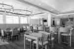 Restaurant dining area with wooden tables, colorful chairs, booth seating, and circular chandeliers.