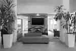 Lobby lounge area featuring a blue sofa, wall-mounted television above a fireplace, potted plants, and armchairs.