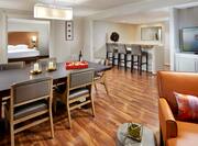 Presidential Suite Living Area With TV, Soft Seating, Dining Table, Open Doorway to Bedroom, and Seating at Kitchen Counter