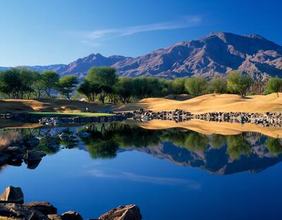 Panoramic view over a lake with mountains in the background. Location is TPC Stadium Course at PGA WEST