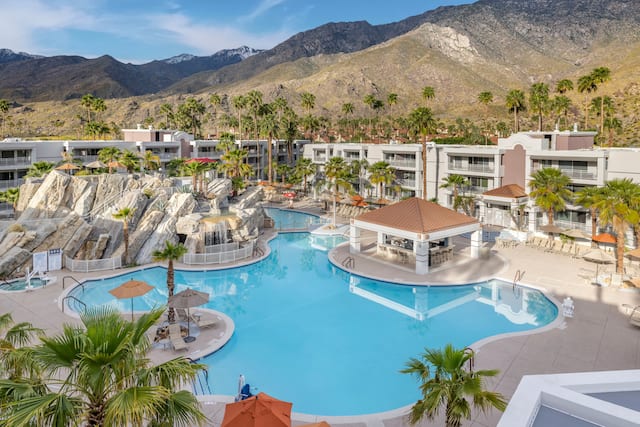 Exterior image from above of pool, poolside bar, guest room buildings, and mountain range.