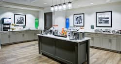Breakfast serving area with buffet trays, coffee, juice, cereals, oatmeal, and dining amenities
