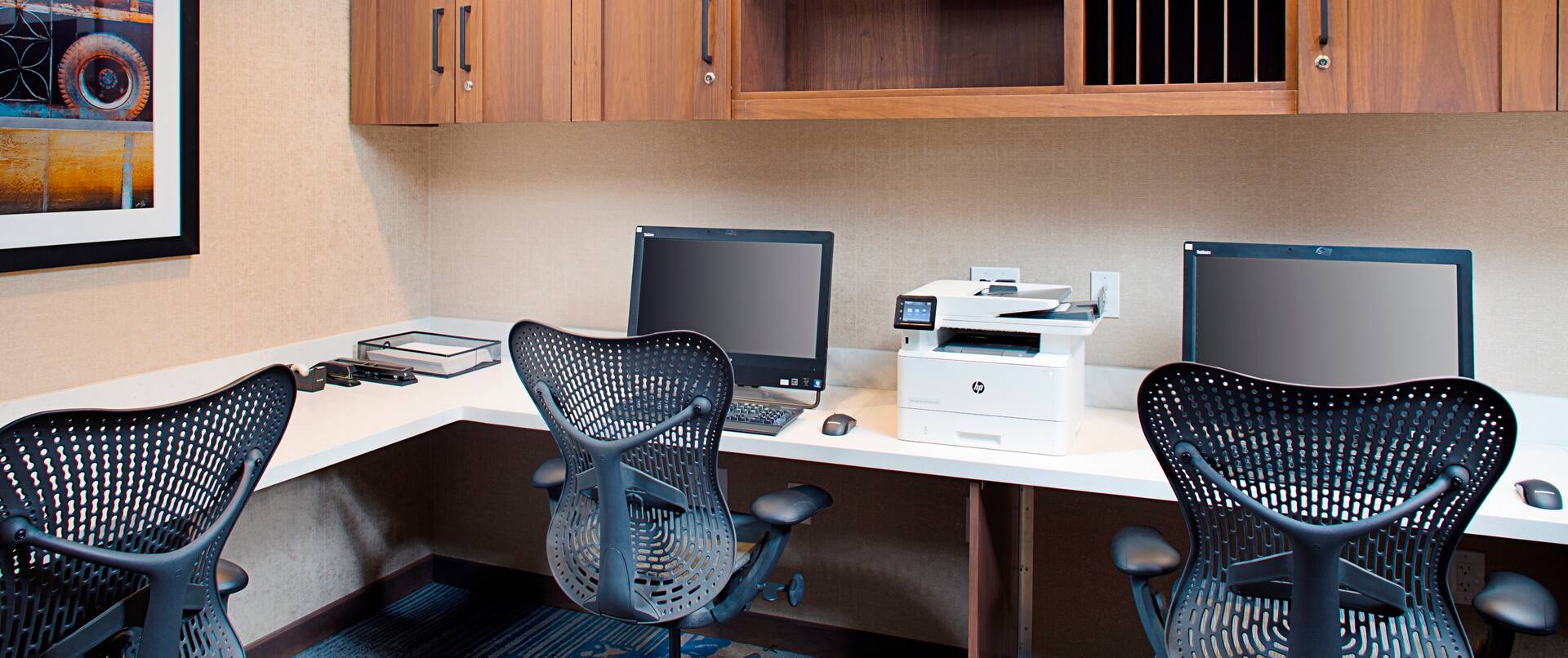 Business Center With Wall Art and Storage Cabinets Above Three Computer Workstations, Ergonomic Chairs, Wall Art, and Printer/Fax/Copier