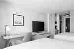Guest room with two beds, a desk and chair, a TV, and an open closet area