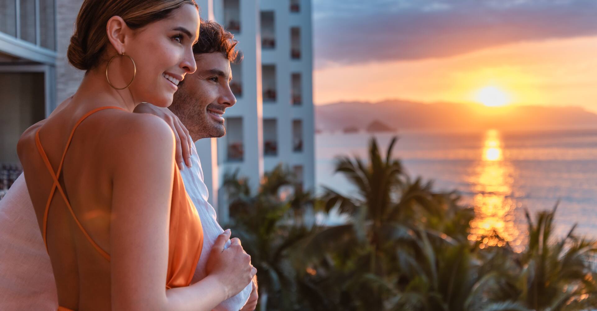 A couple enjoying the view from their guest room balcony at unset