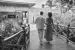 Man and woman walking across wooden bridge. The man has his hand on the woman's back