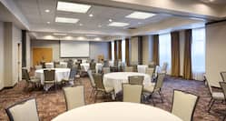 Meeting Room With Presentation Screen, Podium, Chairs and White Linens on Banquet Tables 