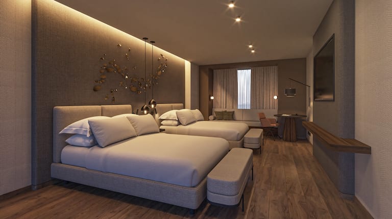 Habitación con dos camas Queen, televisor montado en la pared y sofá