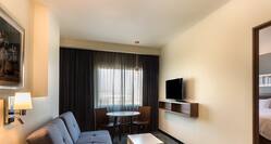 1 King Suite Living and Dining Area With Sofa, TV, Tables and Open Doorway to Bedroom