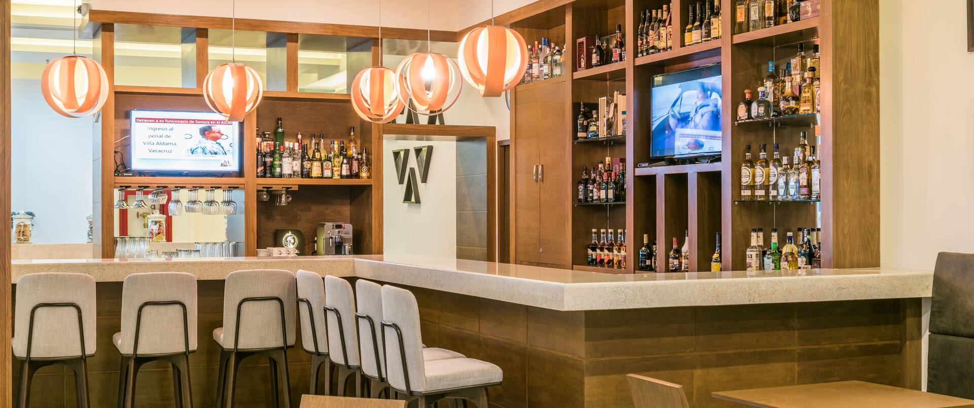 Televisores y sillas junto a la barra en un bar bien surtido con mesas, sillas y asientos en cubículos en restaurante