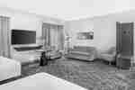 Studio suite with two beds, a sofa, work desk, and a wall-mounted TV.