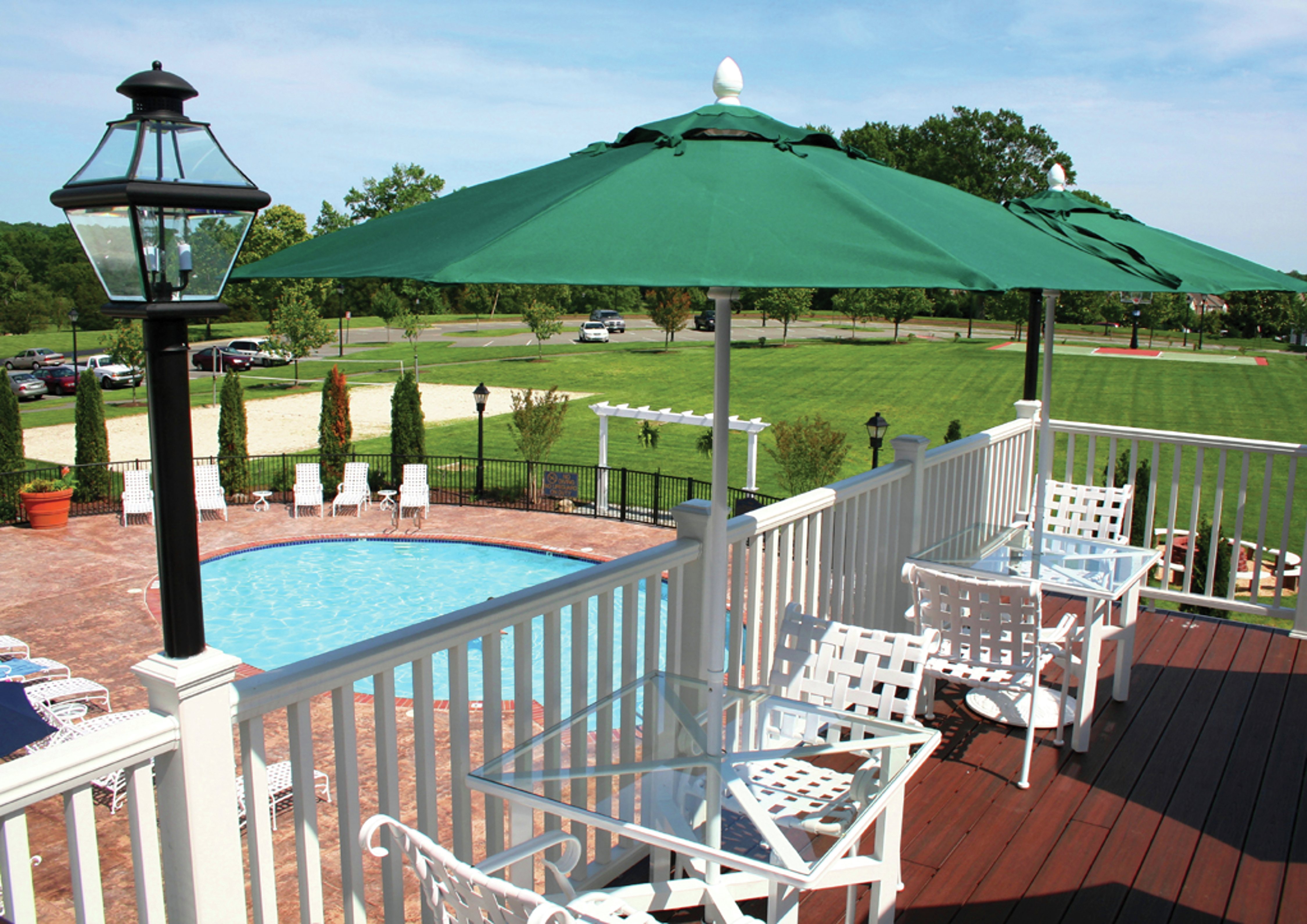 Deck with Umbrella-Covered Tables Overlooking Pool and Field