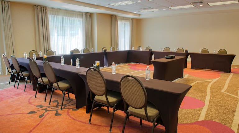 Meeting Room With Bottled Water on U-Shaped Table, Chairs, and Projector Table