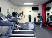Fitness Center With Exercise Equipment, Entry, Water Cooler, TV, and Large Mirror on a Red Wall