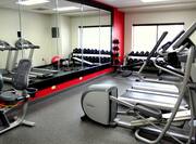 Fitness Center With Cardio Equipment, Large Mirror, Weight Balls, Free Weights  by Window With Open Blinds, Bench, and Red Stability Ball