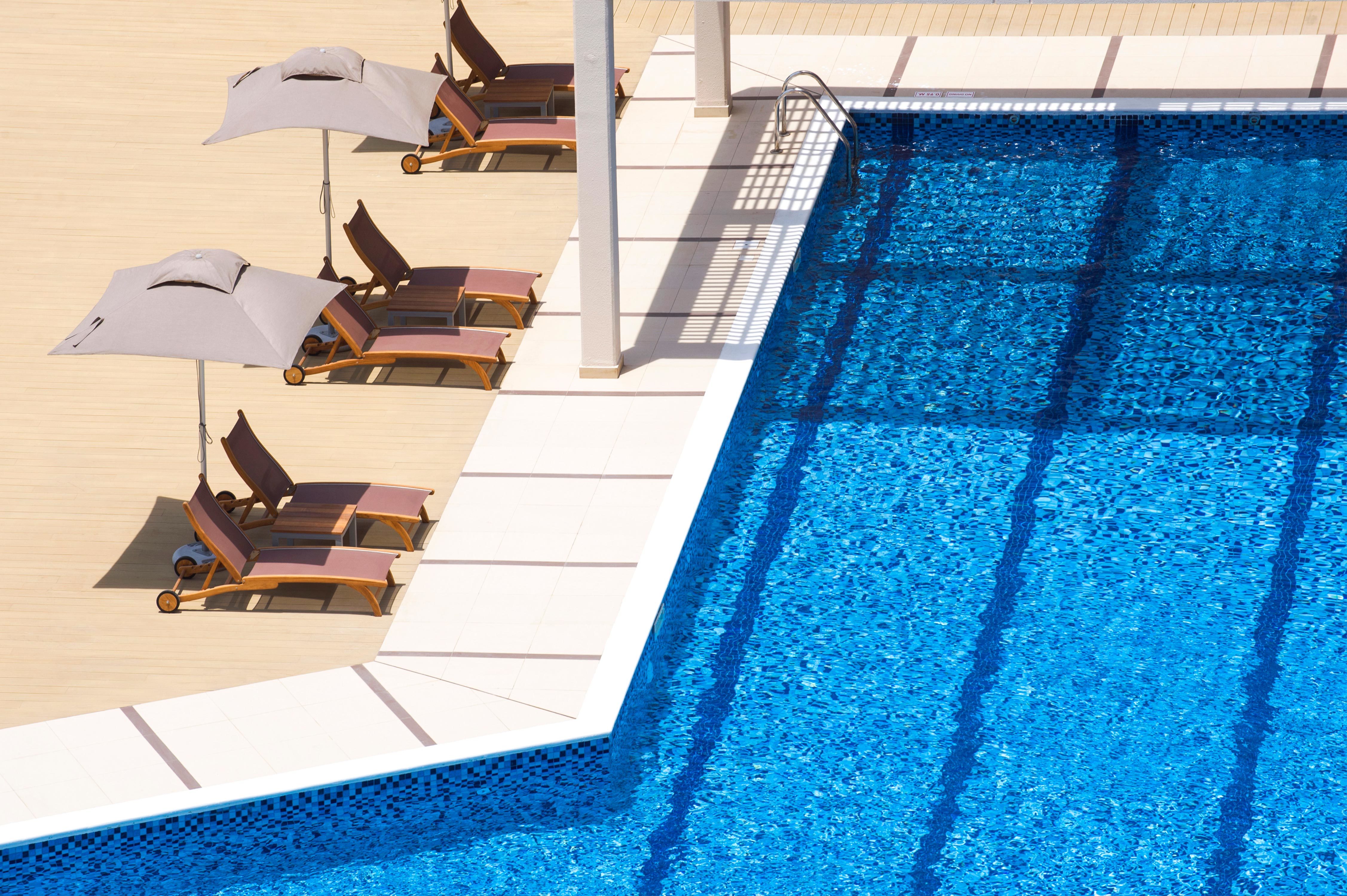 Daytime View of Loungers With Umbrellas by Outdoor Pool
