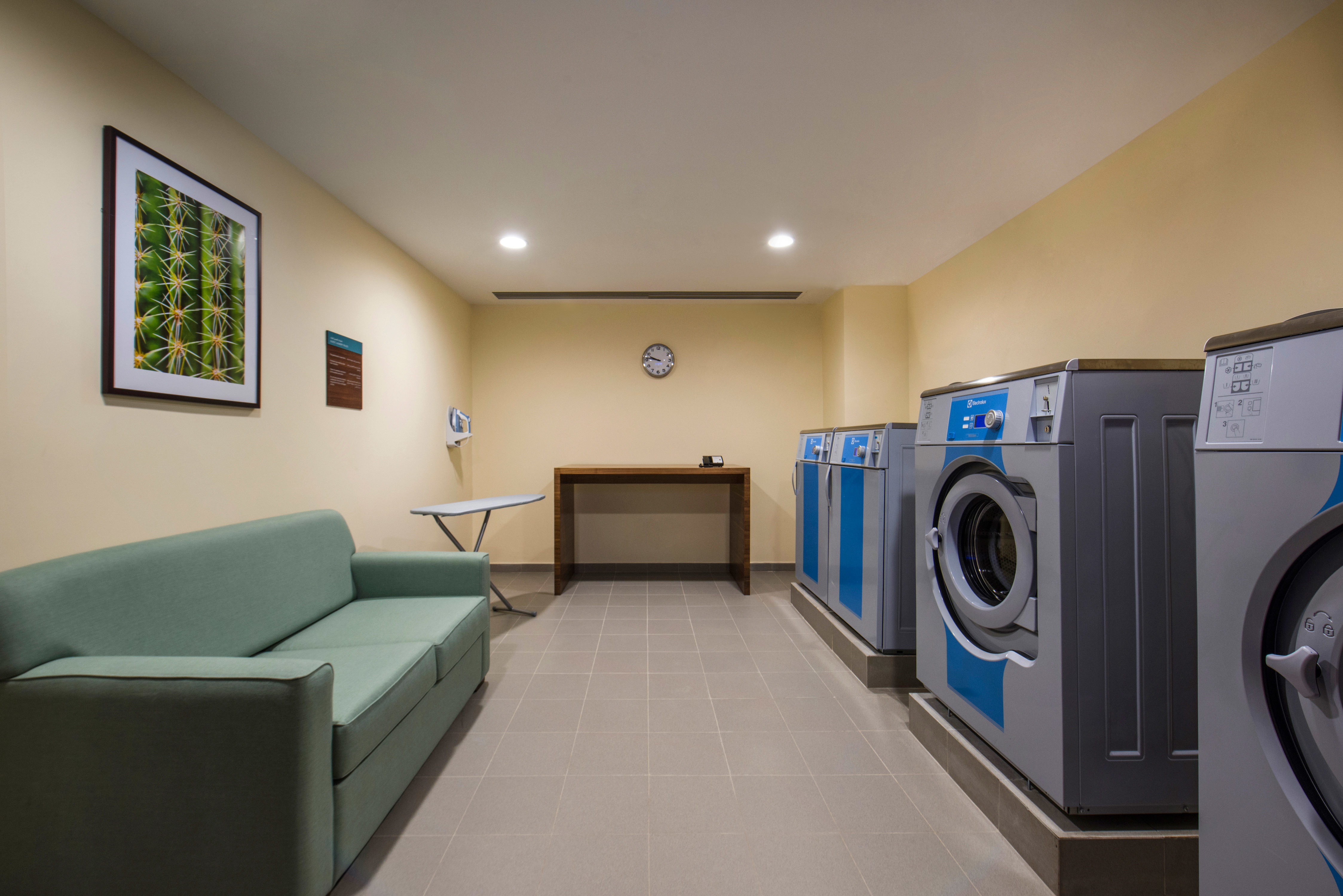 Coin Operated Washing and Drying Machines, Green Sofa and Folding Table in Laundry Facility