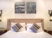 Close-Up of One King Bed with Art Detail and Bedside Lamps in Guest Bedroom