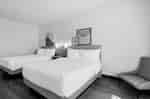 Two-queen guest room with beds, seating area, and contemporary furnishings.