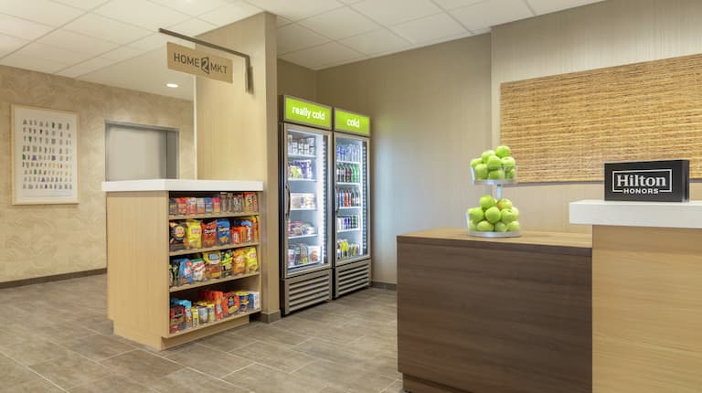 Welcoming front desk in hotel lobby next to convenient on-site fully stocked snack shop.