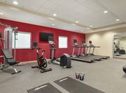 Spacious on-site fitness center for guests featuring weight and cardio machines, exercise bike, and free-weights.