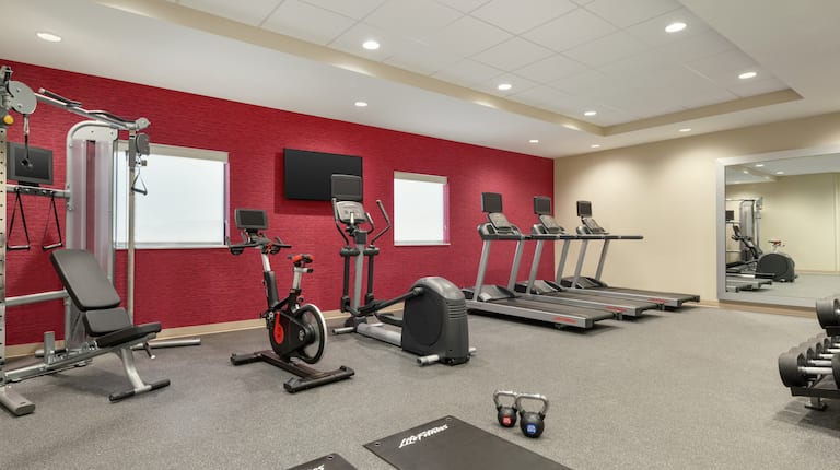 Spacious on-site fitness center for guests featuring weight and cardio machines, exercise bike, and free-weights.