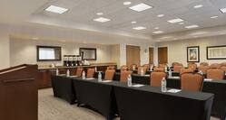 Spacious meeting room fully set with classroom style tables, podium, and coffee break station.