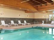 Beautiful indoor pool featuring large windows, ample seating, and hot tub.